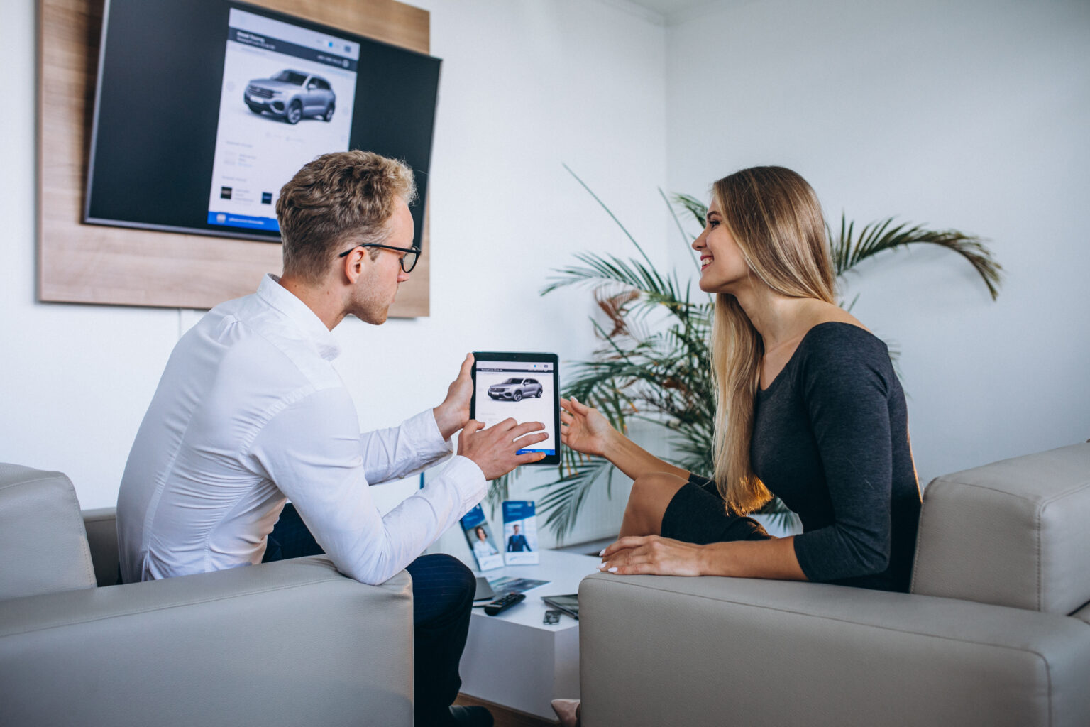 man and woman in a car showroom using tablet